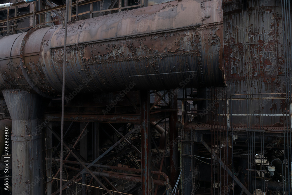 Dark background of rusting metal tubes and pipes, corrosion, industrial backdrop, horizontal aspect