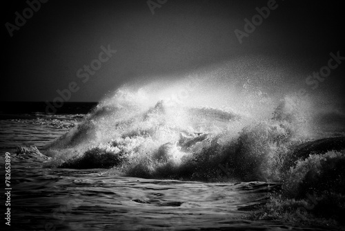 Fototapeta Naklejka Na Ścianę i Meble -  Raging waves crash against the shore, tumultuous and wild, under stormy skies.