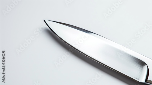 Close-up of sharp kitchen knife blade against white background, highlighting its shiny metallic surface