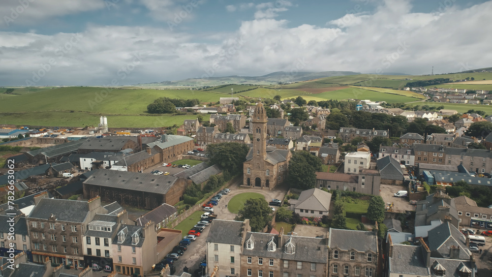 Europe cityscape at traffic road with cars, trucks aerial. Historic buildings at urban streets of Campbeltown city, Scotland. Downtown houses and architecture landmark. Cinematic drone shot