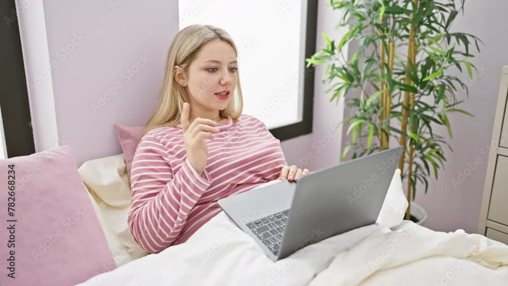 A young woman works on her laptop while relaxing in her bedroom at home, exuding casual comfort and concentration. A young woman works on her laptop while relaxing in her bedroom at home, exuding casual comfort and concentration.