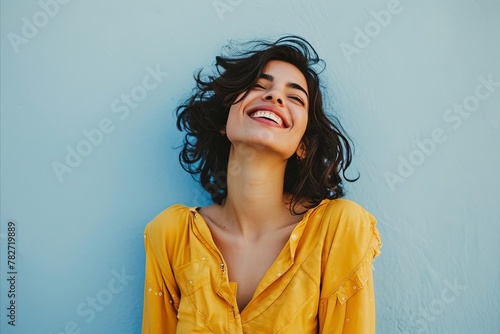 Portrait of a beautiful young woman smiling against a blue background.