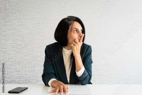 Young caucasian brunette business woman director in office look to side empty space being thoughtful make decisions in office alone at work desk