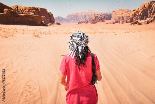 Back view female tourist stand curious watch wadi rum landscape panorama rock formations on sandy road terrain of Jordan countryside. Solitude and explore tranquil landscape
