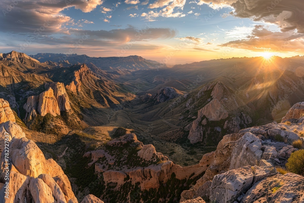 A panorama of a breathtaking sunset over a vast mountain range, showcasing the dramatic peaks bathed in warm light