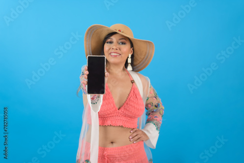 Woman wearing beach outfit showing cell phone screen, selective focus. Blue background.