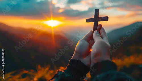 Silhouette of hands presenting Christian cross against sunset