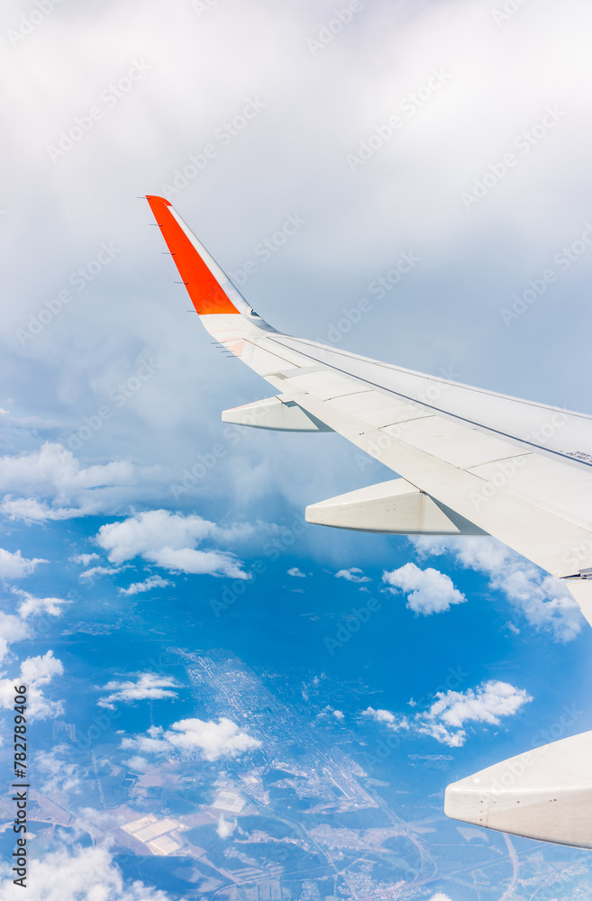 Fototapeta premium View from the airplane window at a beautiful cloudy sky and the airplane wing