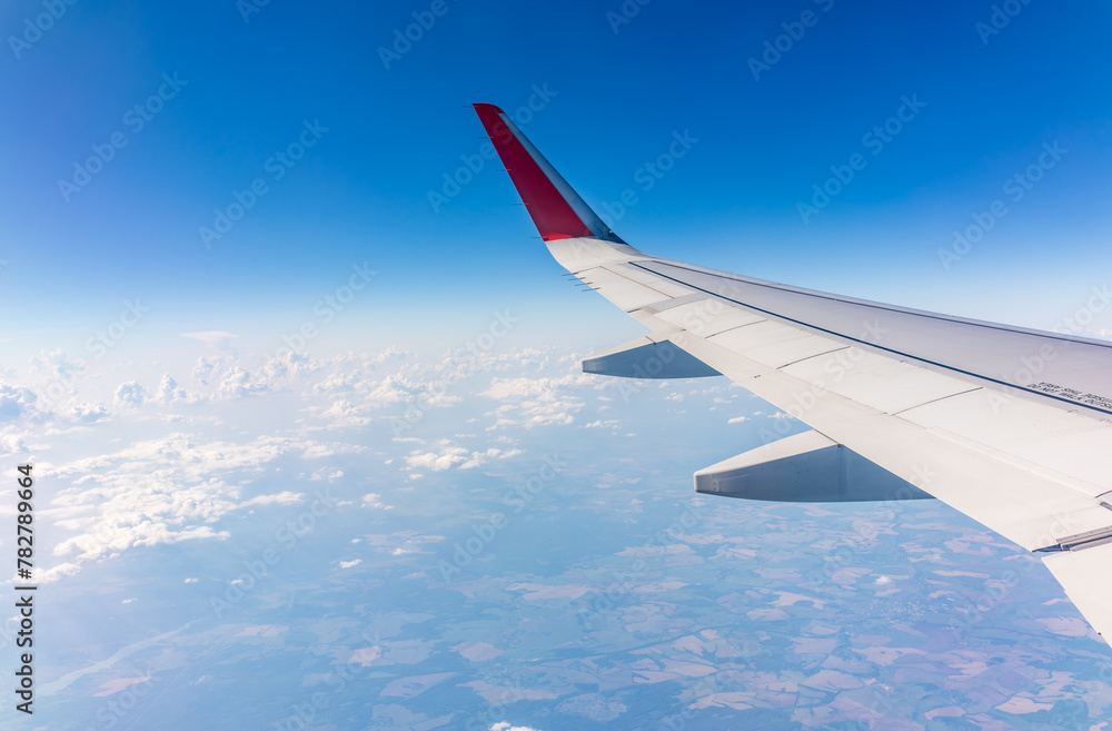 Fototapeta premium View from the airplane window at a beautiful cloudy sky and the airplane wing