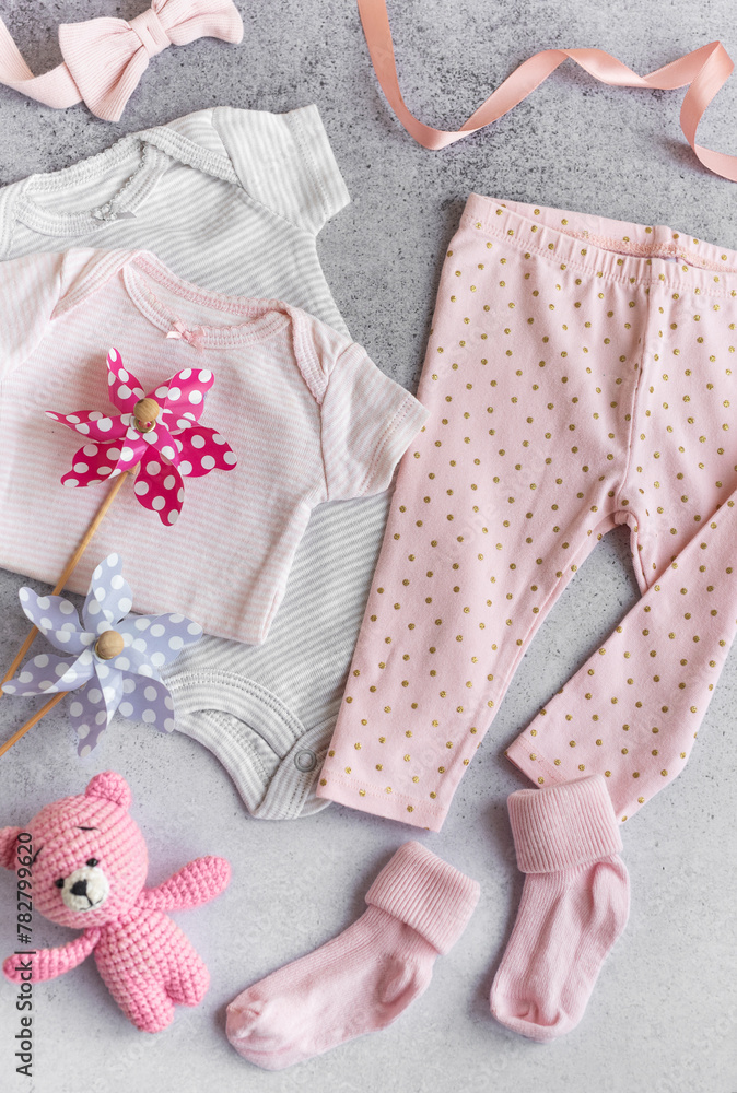 Fototapeta premium Set of baby bodysuits, pants, socks and knitted toy on grey background.