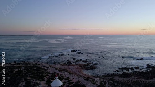 Corny Point lighthouse reverse aerial reveal in evening with flashing light beacon, Yorke Peninsula, South Australia