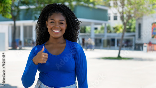 Pretty african american young adult woman showing thumb up with copy space in the city