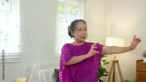 Elderly Asian woman staying at home Exercise according to advice from an online trainer in your home, yoga, pilates class  exercises for good health. Concept of treatment, health care. photo