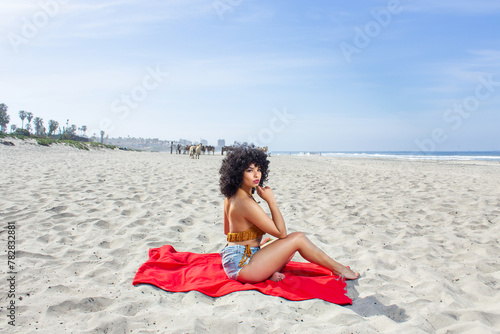 beautiful and sensual latin afro woman sitting on the beach looking at the camera. skin care. basilian model photo