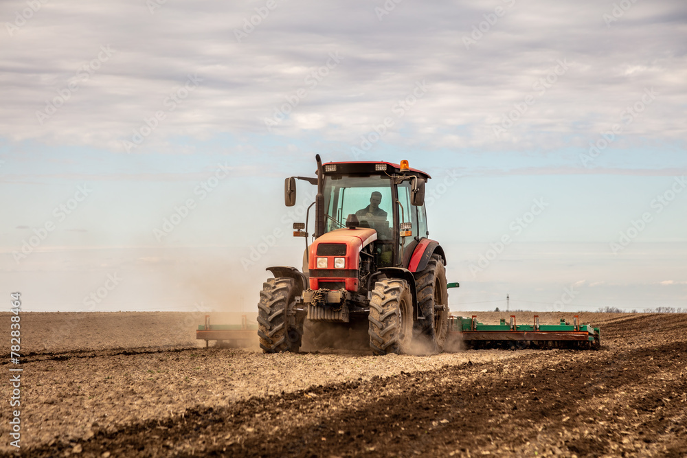 Powerful tractor at work, turning over soil on a vast farmland under a clear sky Powerful tractor at work, turning over soil on a vast farmland under a clear sky