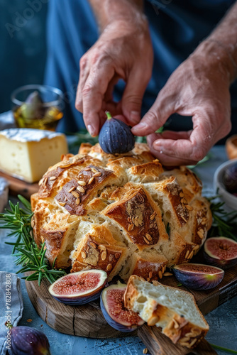 A persons hands slicing into a loaf of bread, surrounded by olives