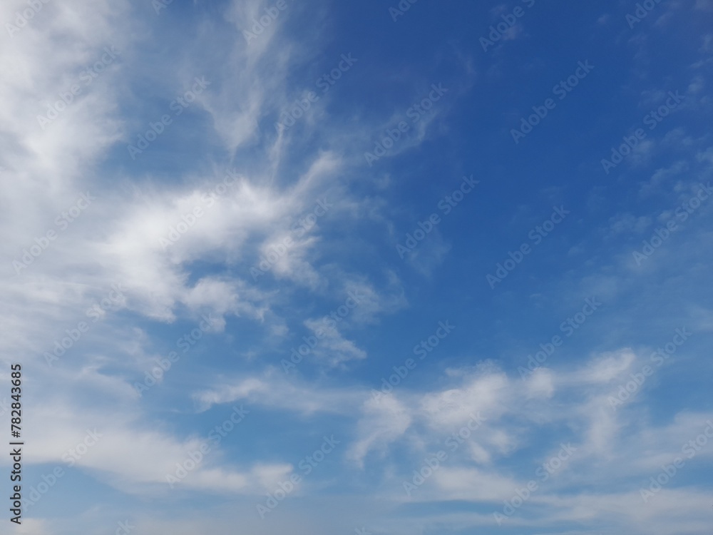 Beautiful white clouds on deep blue sky background. Large bright soft fluffy clouds are cover the entire blue sky.
