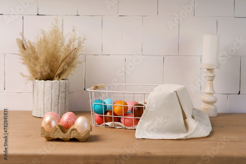 preparation for celebration of Easter. in kitchen, on wooden table is basket with painted eggs, towel, and vase with willow branches. concept Christianity, homely holiday atmosphere, spring holidays © Маргарита Трушина