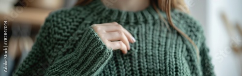 A close-up shot of a person wearing a green sweater, showcasing the texture and details of the knit fabric