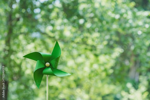 ESG and clean energy paper windmill concept on green background. Sustainable resources. Earth Day. Investing in green businesses. Reducing carbon and creating clean and sustainable energy.
