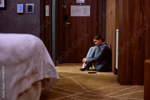 Sad businesswoman sitting on the floor in hotel room. © Drazen