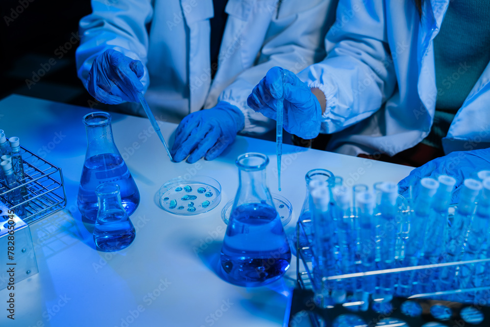 Fototapeta premium Science and medicine, scientist analyzing and dropping a sample into a glassware, experiments containing chemical liquid in laboratory on glassware, innovative and technology.