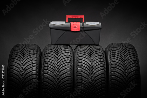Car tires, winter tyres with toolbox case with instruments for car repair isolated on black background