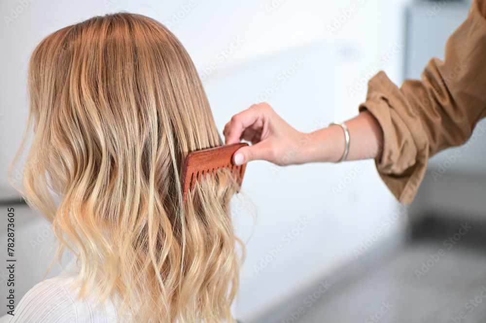 Stylist Combing Through Blonde Highlighted Wavy Hair Stylist Combing Through Blonde Highlighted Wavy Hair