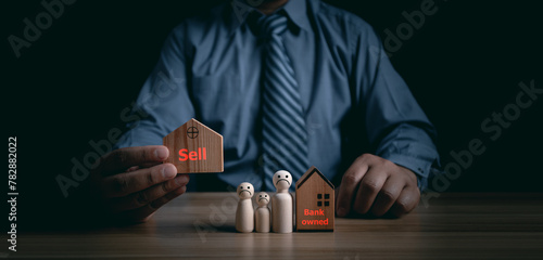 Man holding a wooden house separated from a wooden doll, financial problem concept, bank foreclosure, debt, family problems, Business bankruptcy, divorce, separation, real estate, residential.
