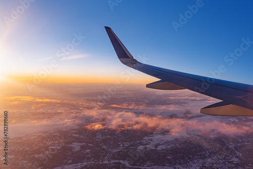 Airplane flying low over snowy mountains and preparing for landing to the airport, view from plane window of wing turbine and skyline © ValentinValkov