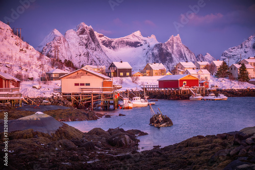 Norwegian fishing village with red rorbu houses, mountain peaks and sea coast winter landscape, Lofoten islands, Norway
