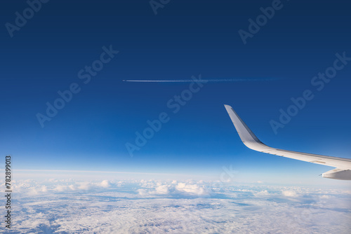 Airplane flying over color sky clouds during scenic sunset or sunrise cloudscape, view from plane window of wing turbines and horizon © ValentinValkov
