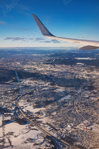 Airplane flying low over snowy mountains and preparing for landing to the airport, view from plane window of wing turbine and skyline