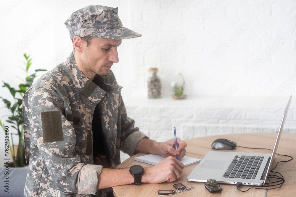Young hispanic man army soldier using laptop sitting on table at home