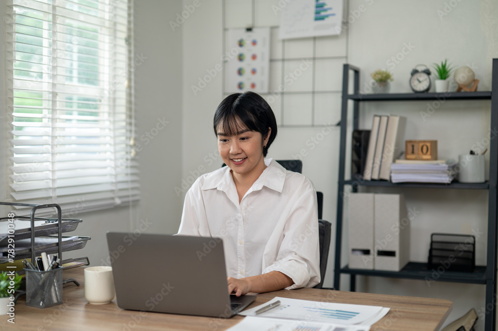 Cheerful businesswoman in white shirt using smartphone with laptop and documents on her office desk. Cheerful businesswoman in white shirt using smartphone with laptop and documents on her office desk.