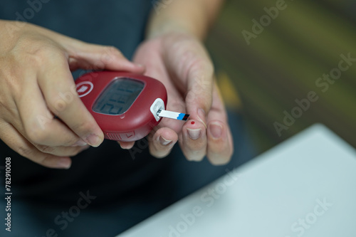 Close-up of hands using a glucometer to check blood sugar level, a crucial part of diabetes management and daily health care.