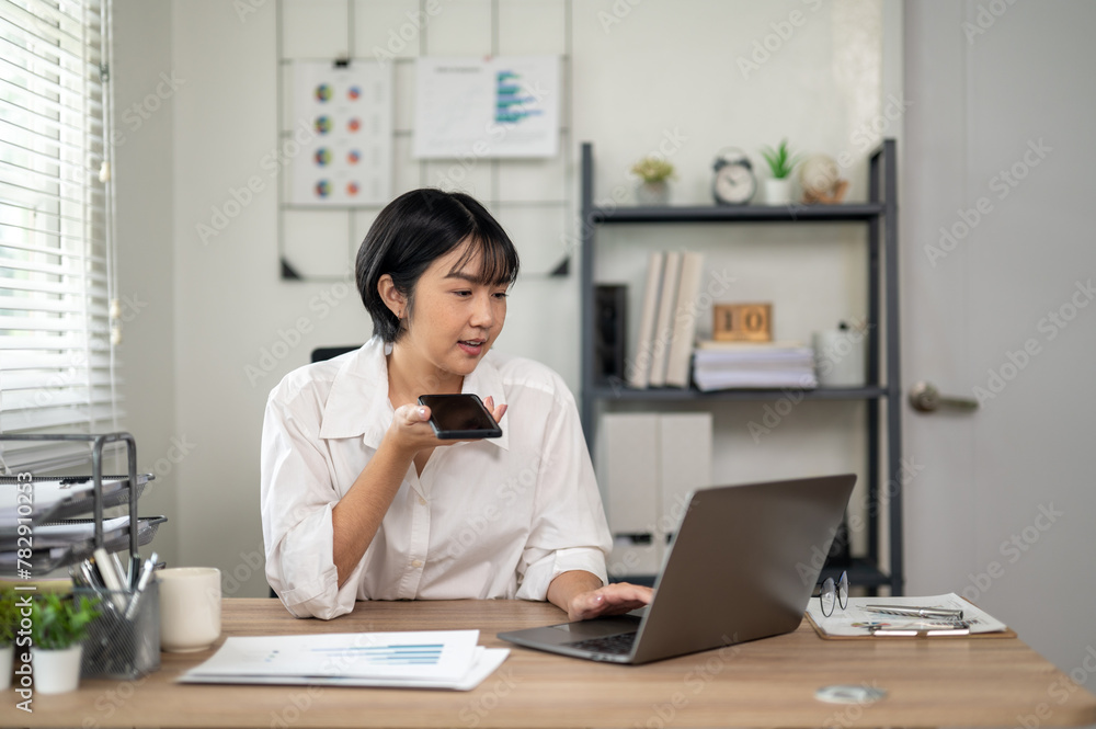 Cheerful businesswoman in white shirt using smartphone with laptop and documents on her office desk. Cheerful businesswoman in white shirt using smartphone with laptop and documents on her office desk.