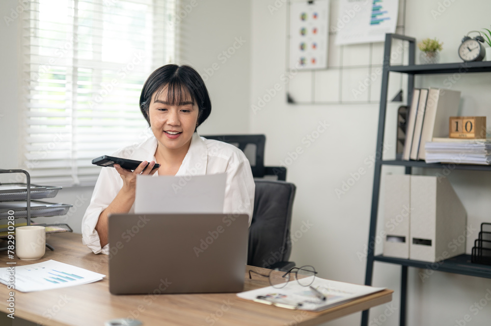 Cheerful businesswoman in white shirt using smartphone with laptop and documents on her office desk. Cheerful businesswoman in white shirt using smartphone with laptop and documents on her office desk.