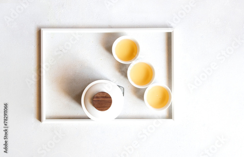 Top view of minimalist composition with Oriental Tea set, teapot , cups and tea leaves on white frame