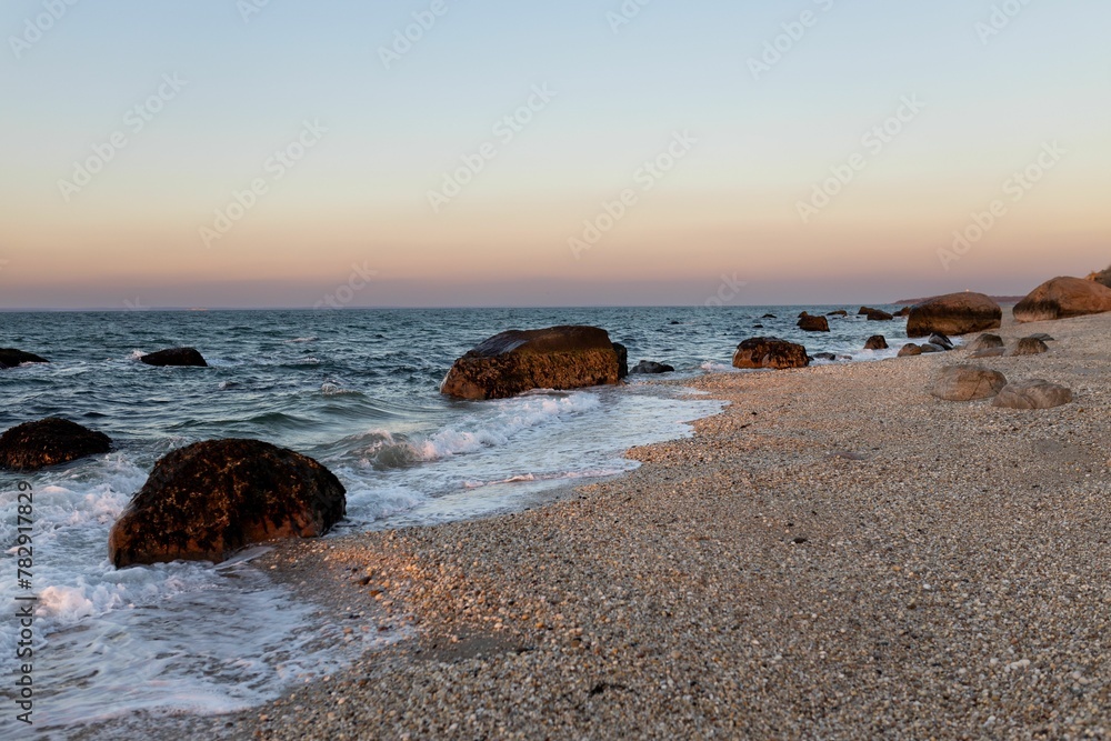 Fototapeta premium Beautiful view of rocks on a beach with clear sky during sunset
