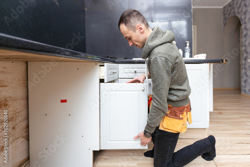 Older man disassembling apartment kitchen out of service photo