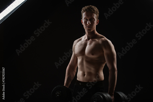  Muscular man with dumbbells on black background. Muscular man with dumbbells on black background.  Absolutely unedited RAW file. No body and environment retouched photography.
