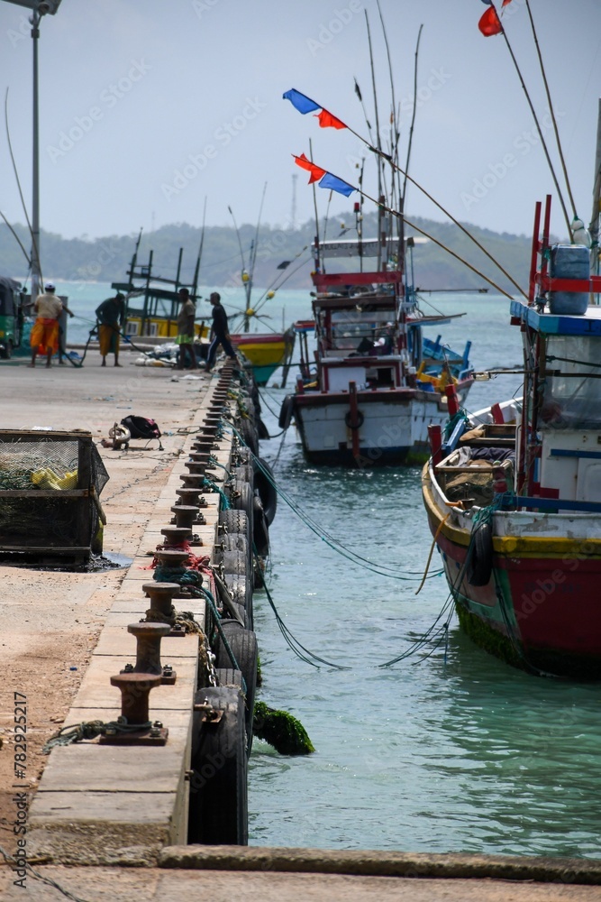 Vertical shot of a port with parked fishing boats  and blue sky in the background