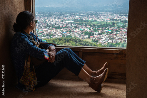 Woman sitting on the windowsill and watching the aerial view of Srinagar in Jammu and Kashmir, India
