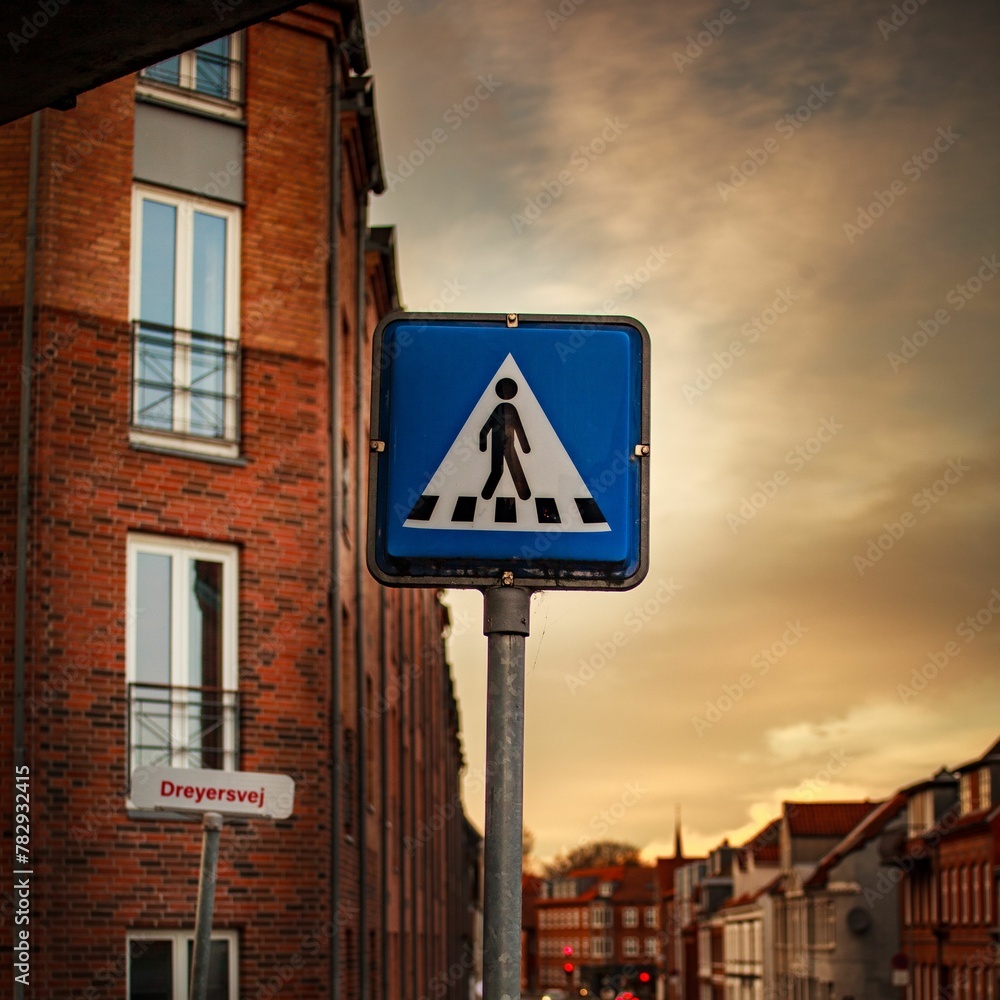Selective focus of the road zebra crossing sign in the street surrounded by brick buildings