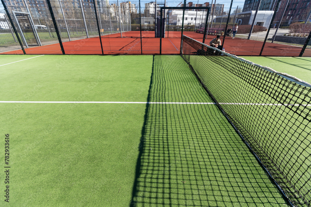 Landscaped areas of a residential development with a tennis court with high Plexiglas and metal fences