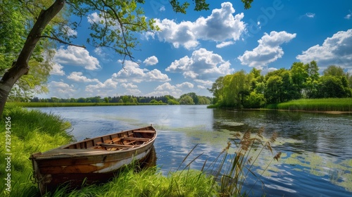 summer landscape with a serene lake, a wooden rowboat moored on the lush green shore, under a vibrant blue sky with fluffy clouds.