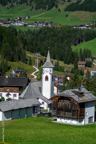 Vertical shot of a tower in the Calfosch village in Italy surrounded by green trees on a sunny day photo