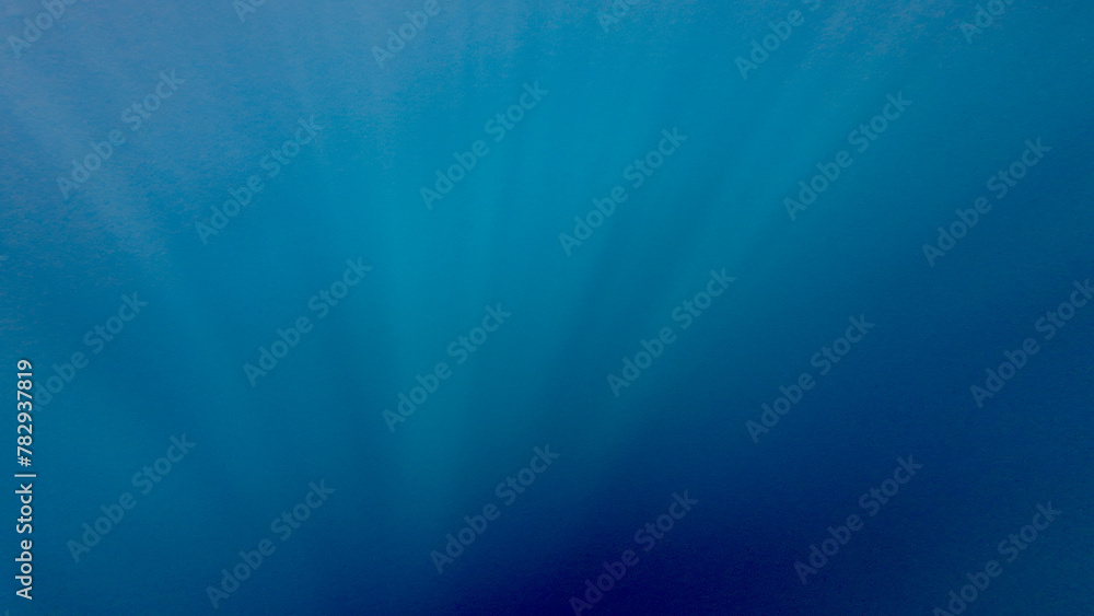 Underwater scene with rays. Underwater blue background. Underwater texture. The sun's rays pass through the water. View of the blue abyss. Inside the ocean.