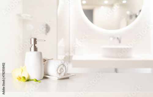 Soap dispenser and towel on table with free space in blurred bathroom